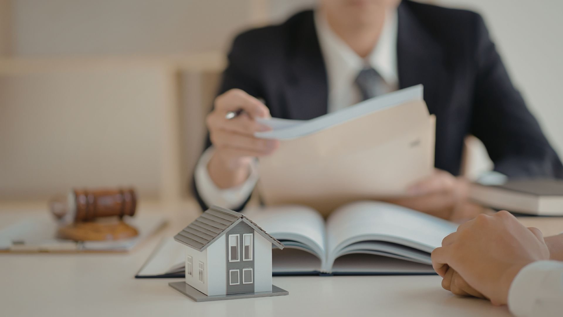 Business professional reviewing legal documents with miniature house model