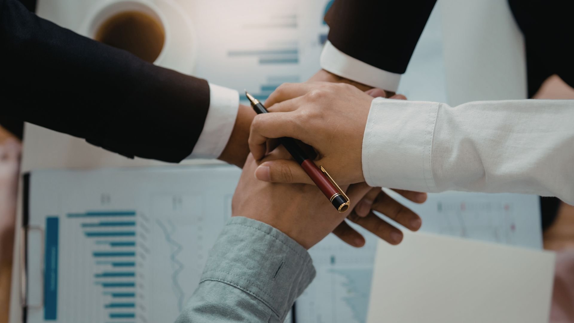 Business professionals shaking hands over documents with pen